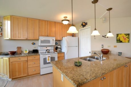 A Fully Loaded Kitchen Features - White full-sized refrigerator, hanging pots and pans for cooking, a full size stove, microwave, and granite countertops create the luxurious living you desire.